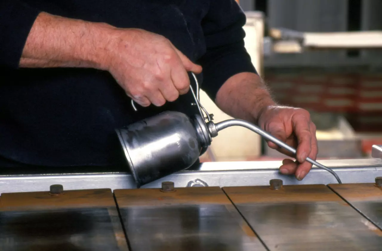 Man's hands hold oiler can, applying lubricant to bakery oven conveyor belt. Shot at Middle East Bakery in Methuen, Massachusetts, USA. C-40 High Temp Chain Lubricant IBU B/Transportation/Energy/Fabrication Industry/Current/G.I.