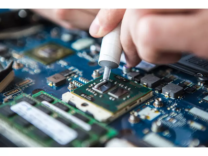 Person applying thermal paste on an electronic motherboard