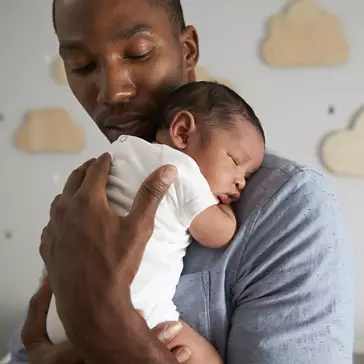 Father Holding Newborn Baby Son In Nursery