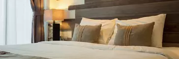 Empty double bed and lamp on side of bed in luxury in a natural style bedroom decorated with wooden boards.