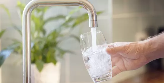 Filling up a glass with clean drinking water from kitchen faucet