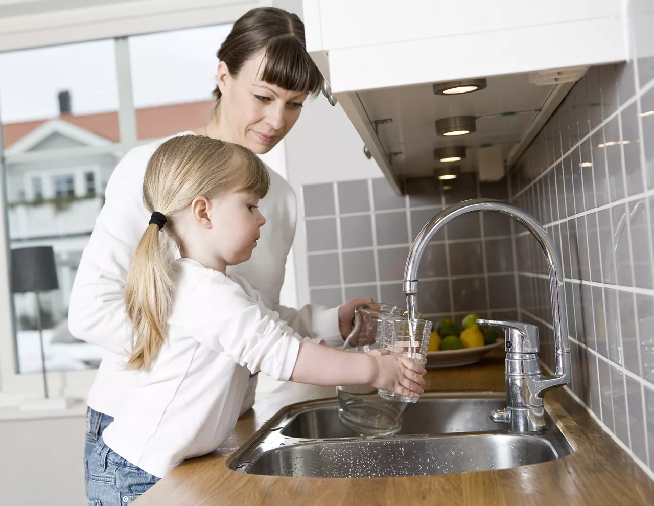 Girl in the kitchen with her mother getting a glass of water