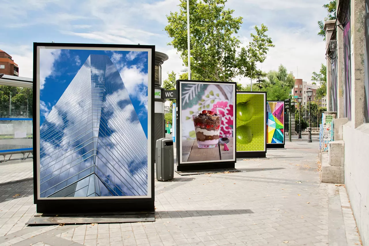 Four billboards with photographs exhibited at city street.