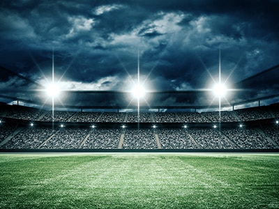 rendering of a stadium with lights on and cloudy sky in background