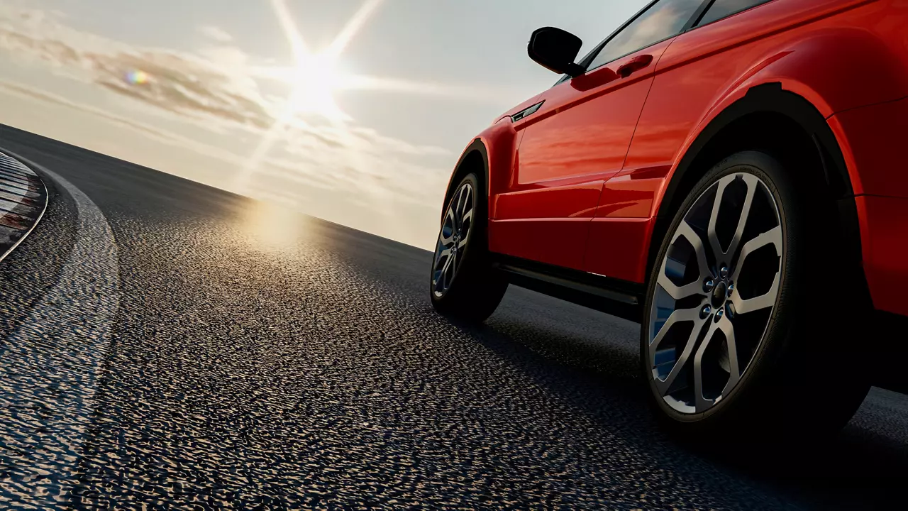 Red car drives on the road toward sunset