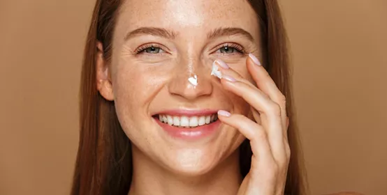Beauty image of woman smiling and applying face cream