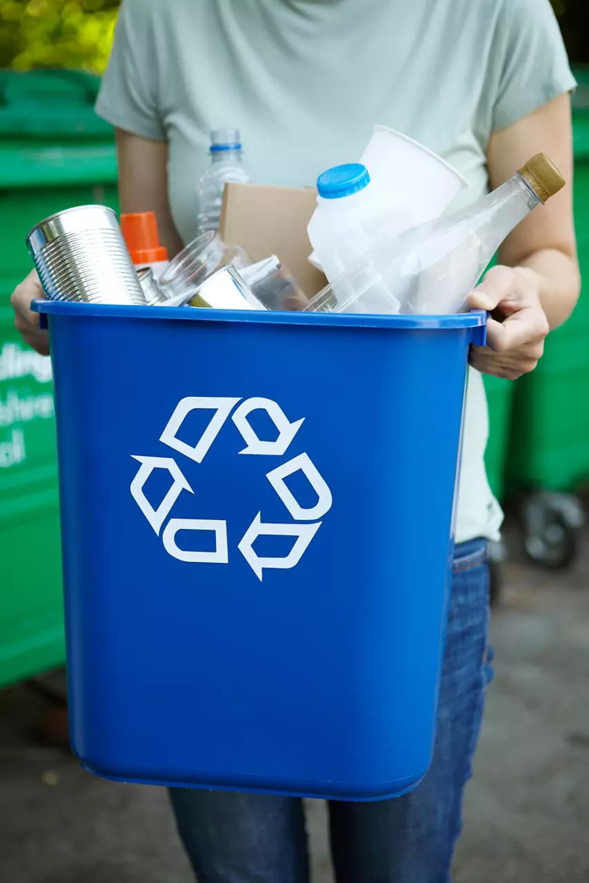 Woman Carrying Blue Recycling Bin filled with items