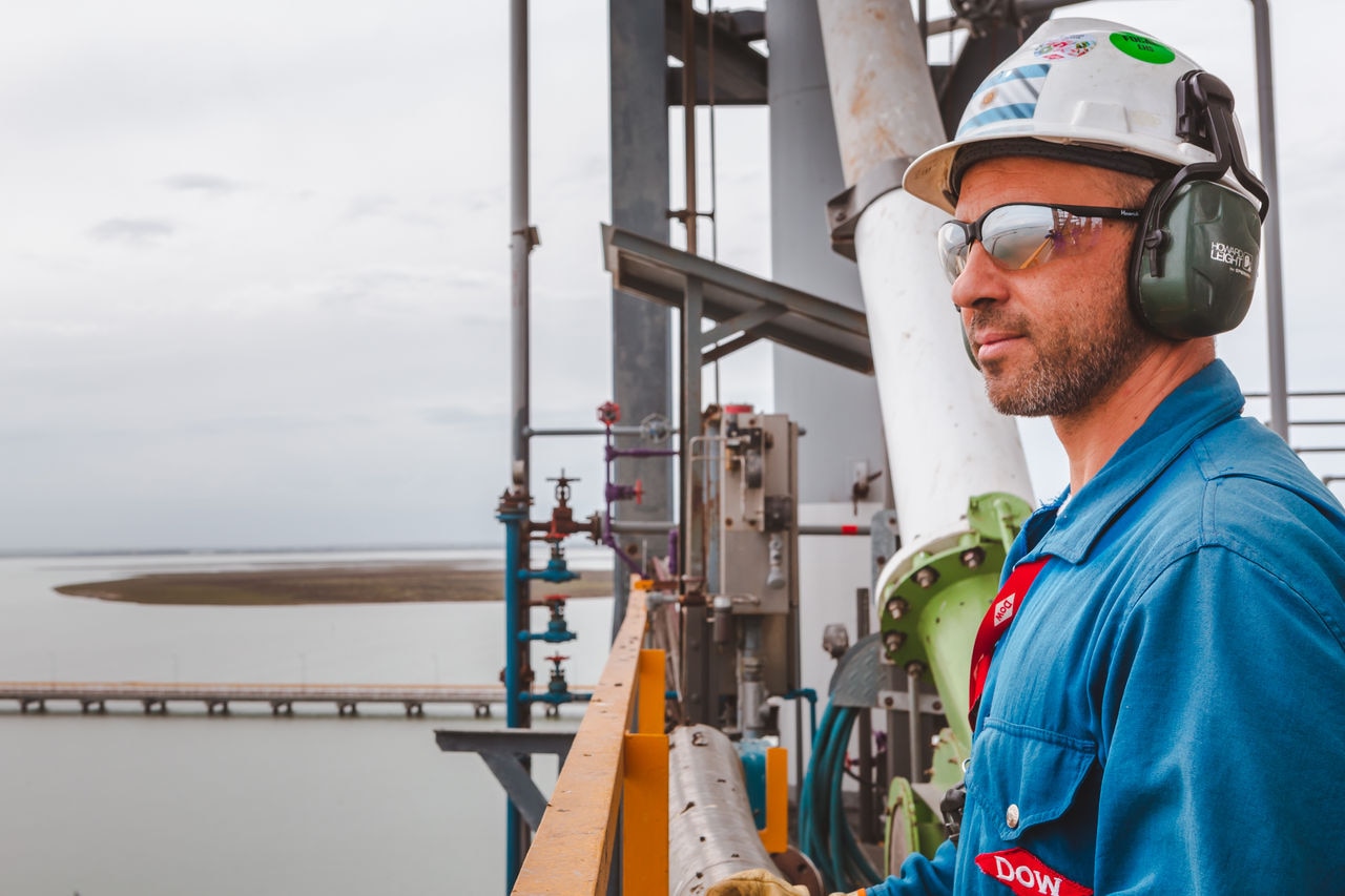 Closeup of a male employee standing outside Bahía Blanca facility, staring into the distance.