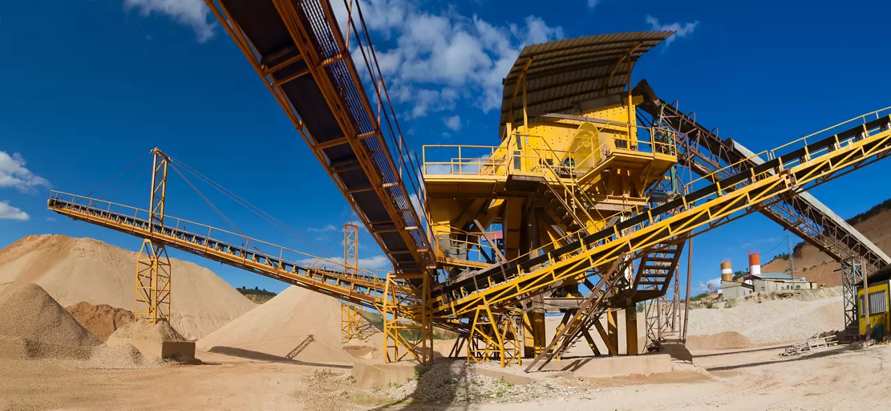 Machinery and classification according gravel size distribution via conveyor belts and piles of sand and records in mountain landscape